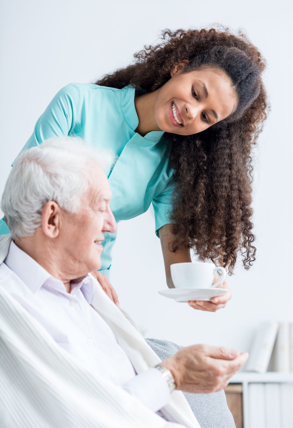 Hydration & compassionate care Caregiver offering a glass of water to an elderly woman to support hydration and comfort.